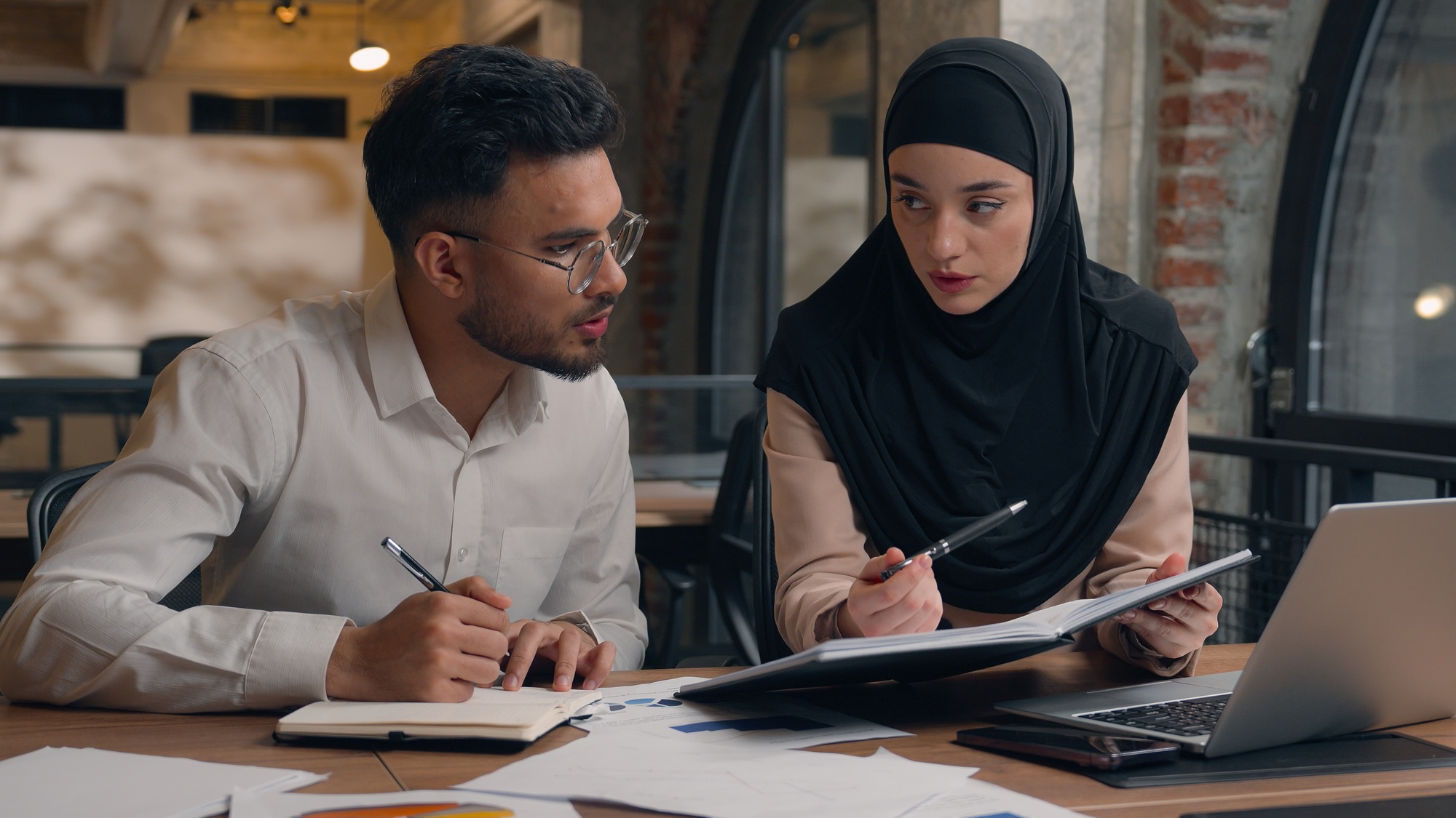 Two business colleagues muslim islamic businesswoman in hijab Arabian businessman working with