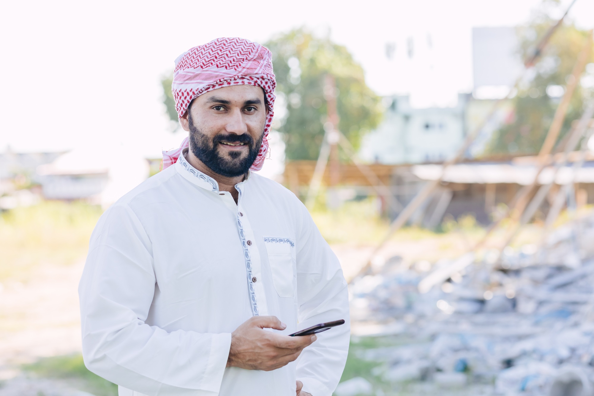 Arab Islam Muslim male from Saudi Arabia portrait happy smile standing outdoors with smart phone