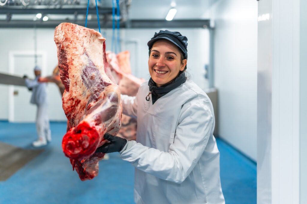 Butcher carrying meat in cold store of a slaughterhouse