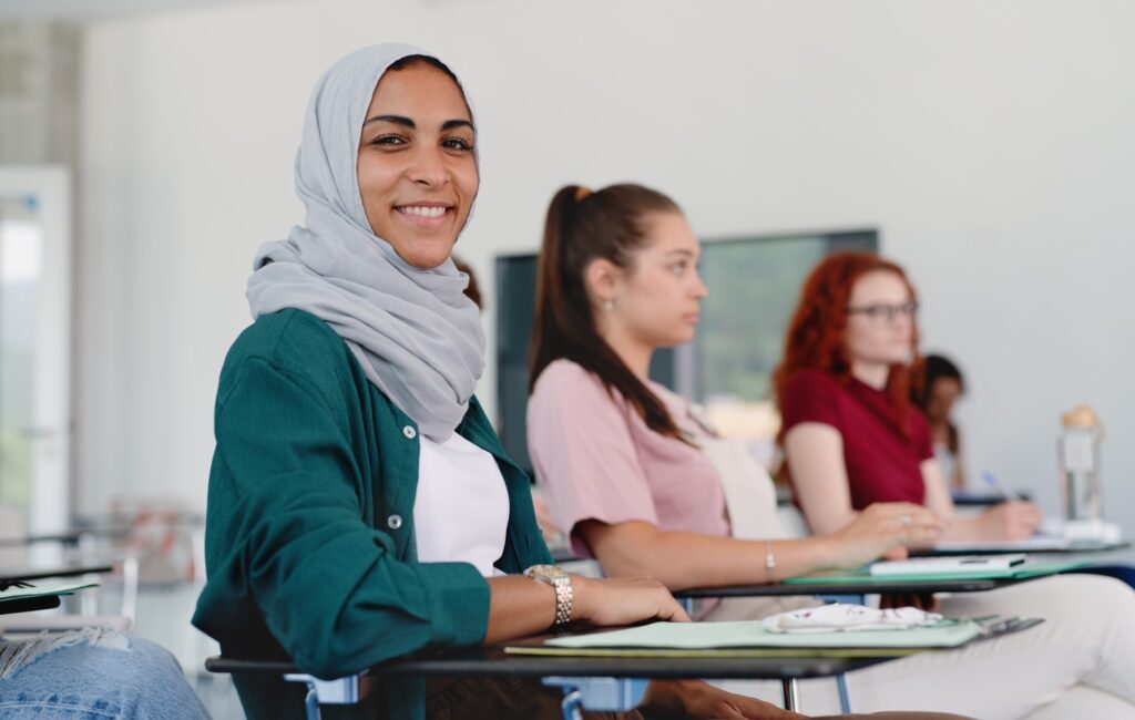 Portrait of islamic university student sitting in classroom indoors, looking at camera